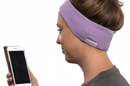 woman wearing lavender SleepPhones sleep headphones looking at iPhone app Sleep Sounds