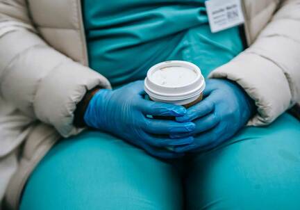 doctor with gloves on holding cup of coffee