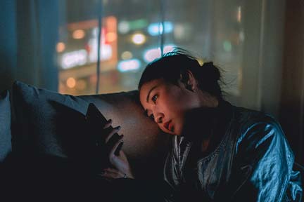girl laying on couch in the evening scrolling on phone