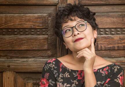 woman with short curly hair and glasses in thinking pose
