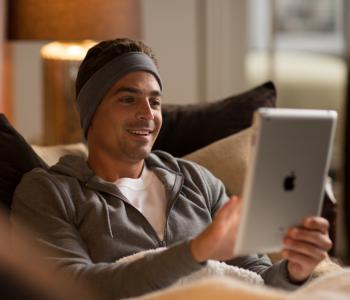 man selecting an audiobook to listen to through sleepphones headphones using a smart tablet