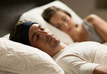 man sleeping with Bluetooth SleepPhones sleep headphones next to snoring partner