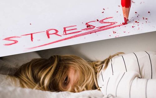 woman laying in bed stressed out she can't sleep with stress written above her in red colored pencil