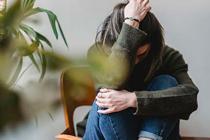 woman with knees tucked to chest and head on hand