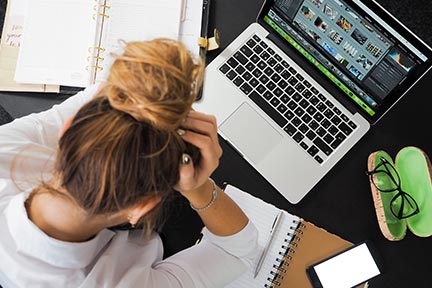 aerial view of girl at desk with laptop open and head on hands frustrated and tired