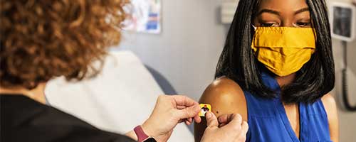 Considering the vaccine booster? A woman in is a medical doctors office receiving the covid vaccine booster.