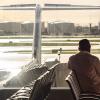 man watching airplane through airport window