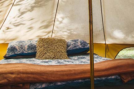 yellow tent with blue and orange blankets and pillows inside