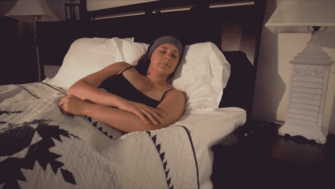 Screenshot of woman wearing SleepPhones, lying next to her husband in bed