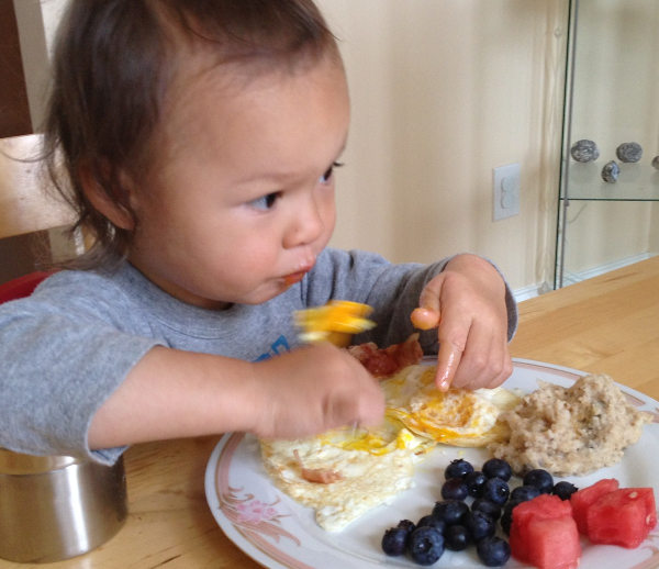 child eating eggs bacon blueberry watermelon oatmeal
