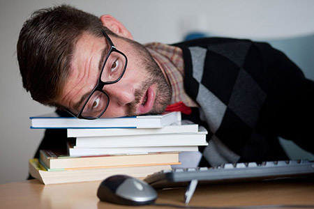 college student sleeping on books