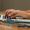 a business person typing on a laptop beside a stethoscope